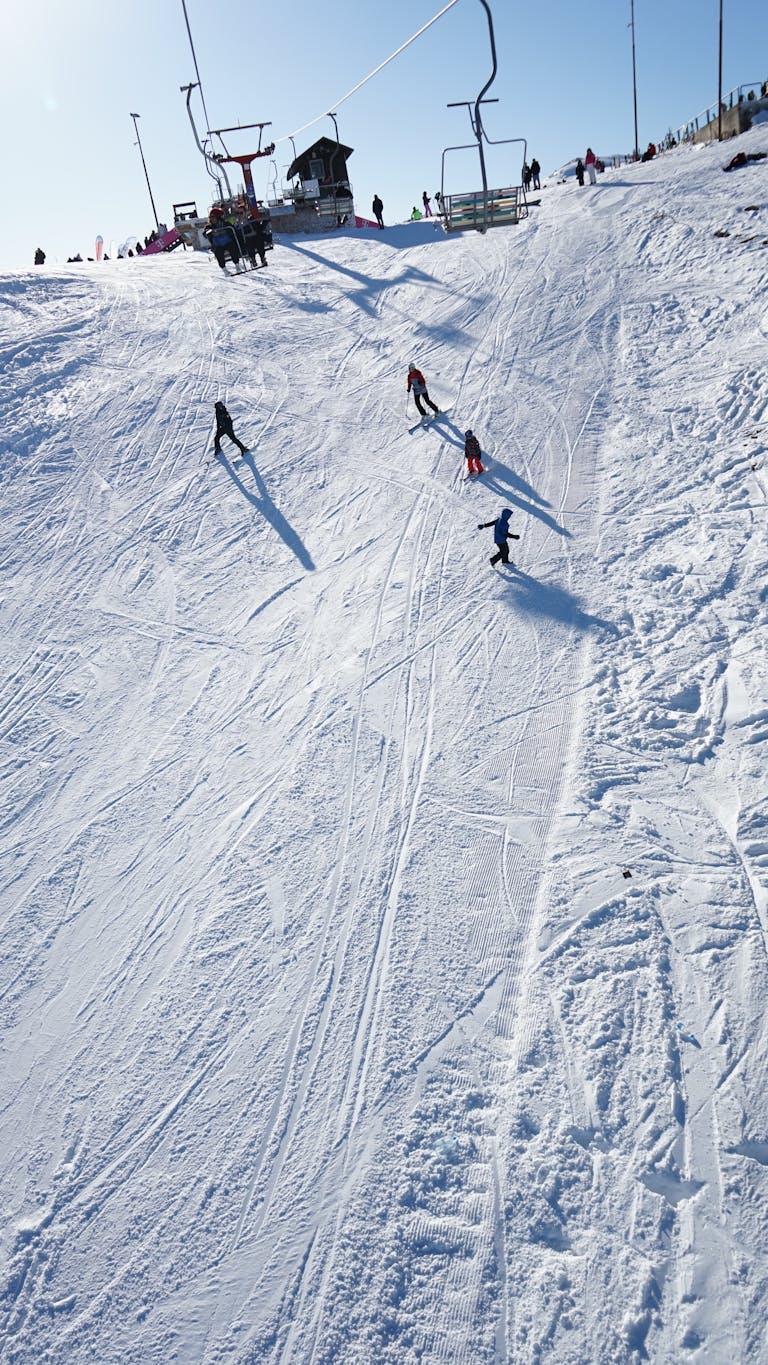Skiers carve through fresh snow on a sunny day in Mavrovo, North Macedonia.