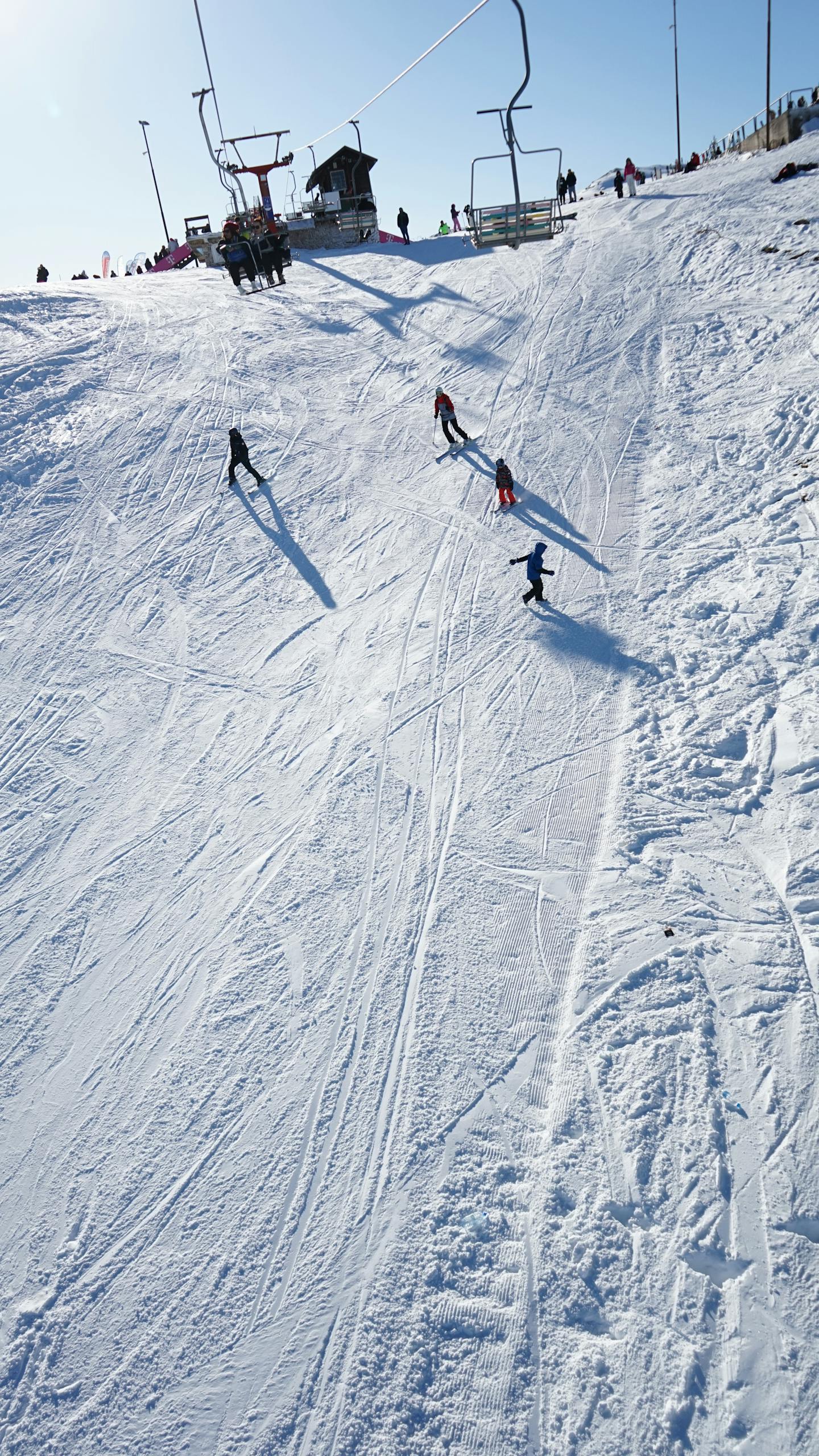 Skiers carve through fresh snow on a sunny day in Mavrovo, North Macedonia.